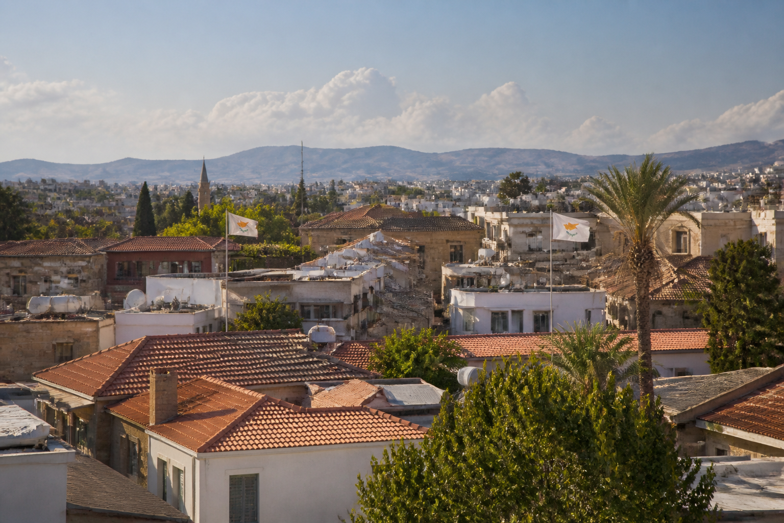 Blick auf die geteilte Altstadt von Nikosia mit Zypern-Flaggen und sommerlichem Himmel