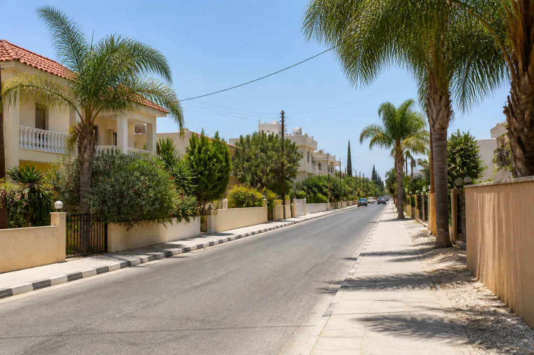 Sommerhitze auf Zypern mit heller Straße, Palmen und Wohnhäusern in Paphos