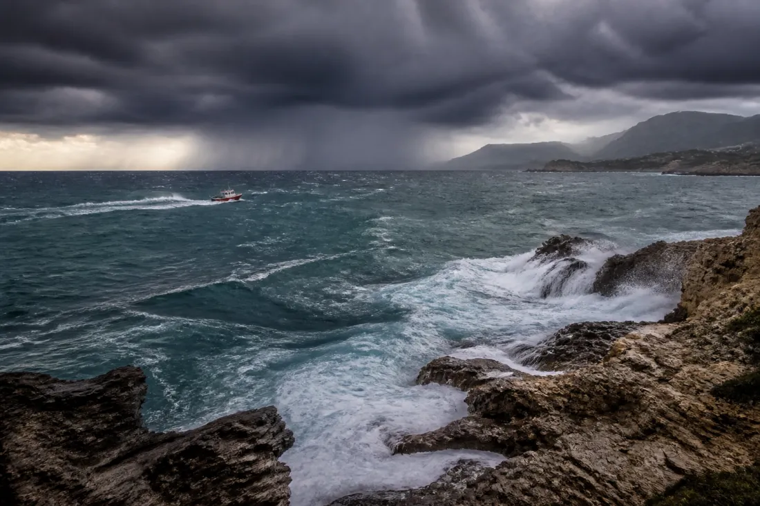 Stürmische Küste bei Kyrenia auf Zypern mit Rettungsbooten in der Ferne und dunklen Gewitterwolken über dem Meer