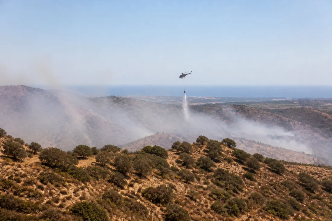 Feuerwehrhubschrauber über trockener Landschaft bei Kalo Chorio und Psevdas auf Zypern