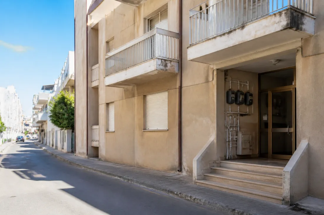 Apartmenthaus in Larnaka auf Zypern mit Stromzählern, Wasserleitungen und Wohnbalkonen als Symbol für Immobilienprüfung und Nebenkostenrisiken