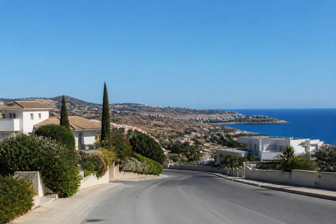 Blick auf die südzyprische Küste bei Limassol mit Straße, Wohnhäusern und weitem Mittelmeerhorizont als Symbol für Sicherheit und Standortwahl auf Zypern